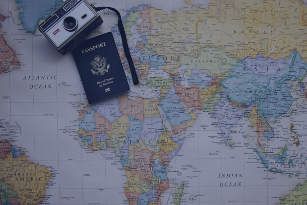 Vintage camera and passport on a world map, symbolizing travel and adventure across continents.