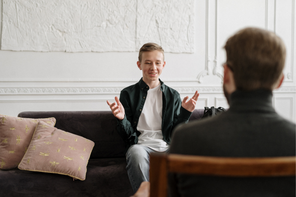 10 Strategies for Overcoming Culture Shock while Studying Abroad in 2026 7 Young man conversing with therapist on couch, engaging in a lively discussion in a bright, comfortable room.