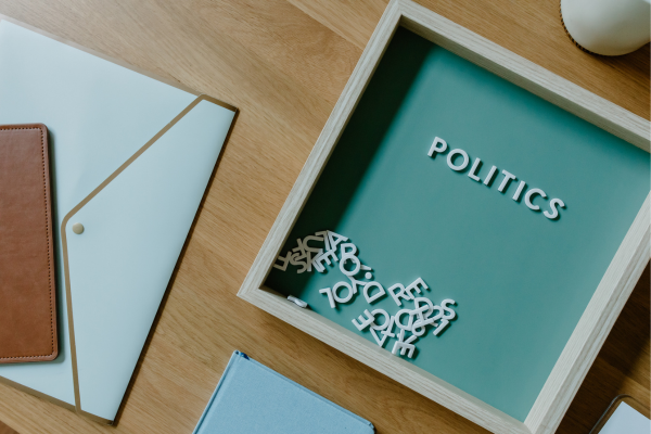 From Data to Diplomacy: Data Science Jobs in Government and Public Policy 7 Wooden frame with scattered letters spelling Politics on a desk next to folders and a notebook.