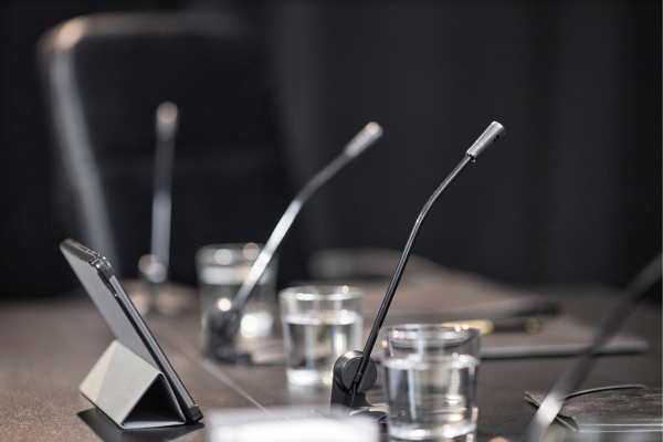 Conference room with microphones, tablets, and glasses of water on a table, ready for a meeting or discussion.