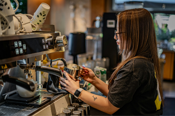 Side Hustles for College Students: Balancing Freelancing with Full-Time Studies 8 College student working as a barista in a café, illustrating one of the most popular side hustles for college students.