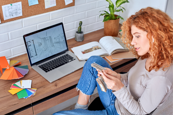 Side Hustles for College Students: Balancing Freelancing with Full-Time Studies 10 Designer reviews color swatches at desk with laptop, design book, and plants. Creative workspace concept.