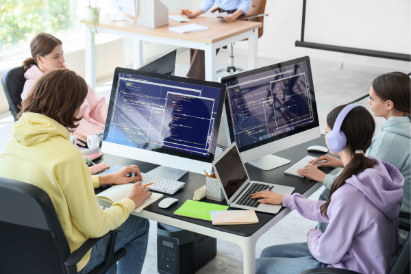 Why Donate to STEM Education? The Ripple Effect of Giving 12 Team of young programmers collaborating, coding on computers in a modern office environment.