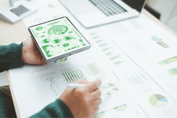 Why Diversity in Business Drives Better Startup Outcomes 9 Person analyzing financial graphs on paper and tablet, highlighting eco-friendly business growth strategies.