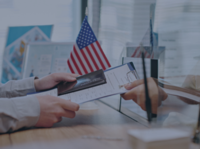 New F-1 Visa Rules for International Students: Your Questions Answered 62 Person hands passport and documents at counter near American flag, representing travel or visa application process.