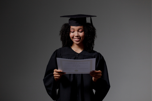 Understanding Cybersecurity Frameworks: Essential Cybersecurity Certification Tips 11 Graduate in cap and gown smiling while holding a diploma, symbolizing achievement and celebration of education.