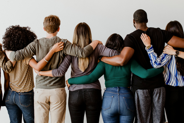 Why Diversity in Business Drives Better Startup Outcomes 8 Diverse group of people standing together with arms around each other, symbolizing unity and support.