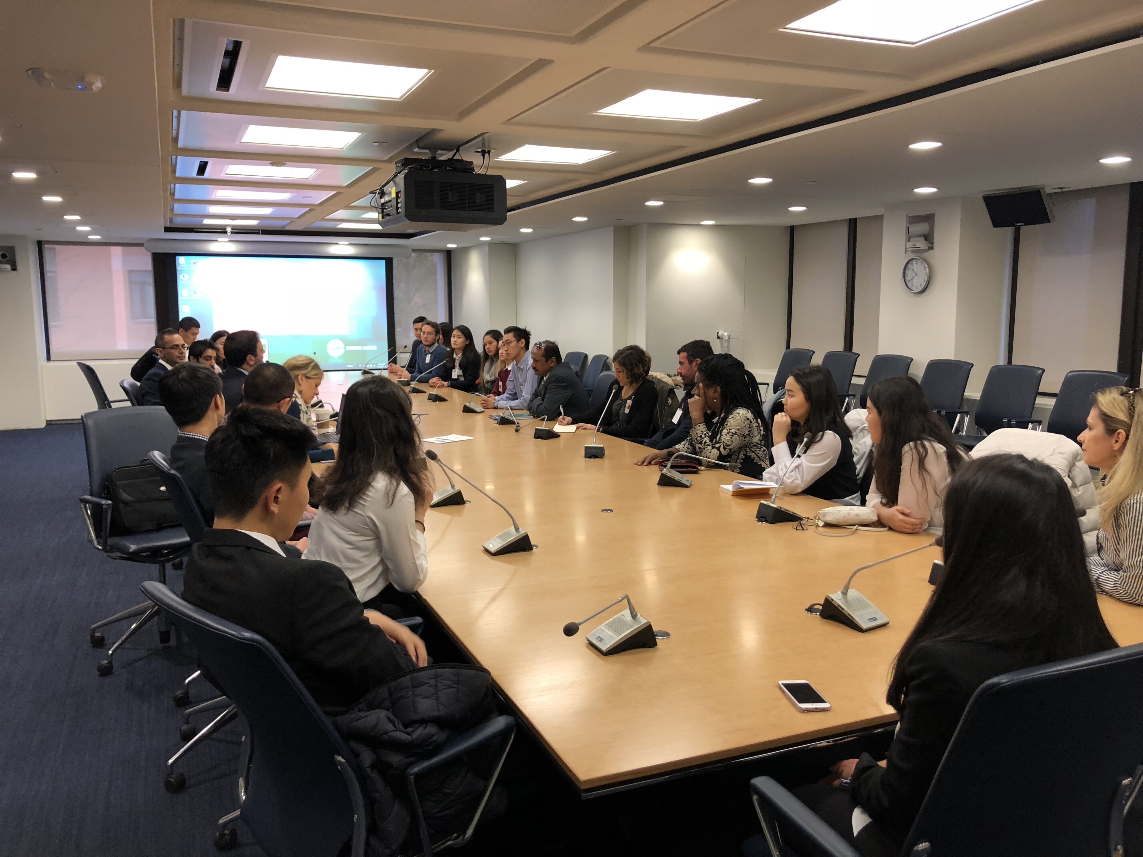 People in a business meeting around a large conference table in an office setting.