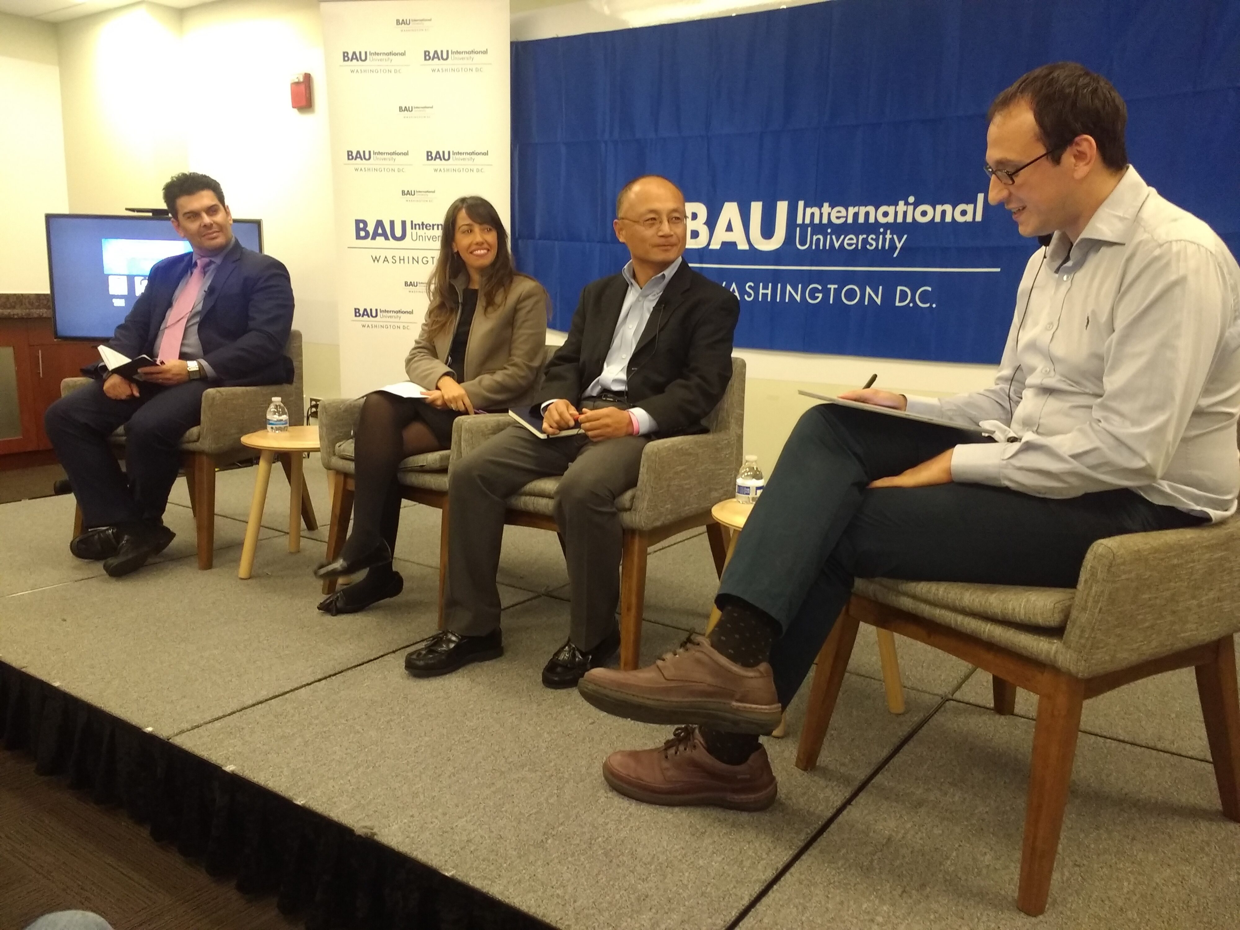 Panel discussion at BAU International University, Washington D.C., featuring four speakers on stage.