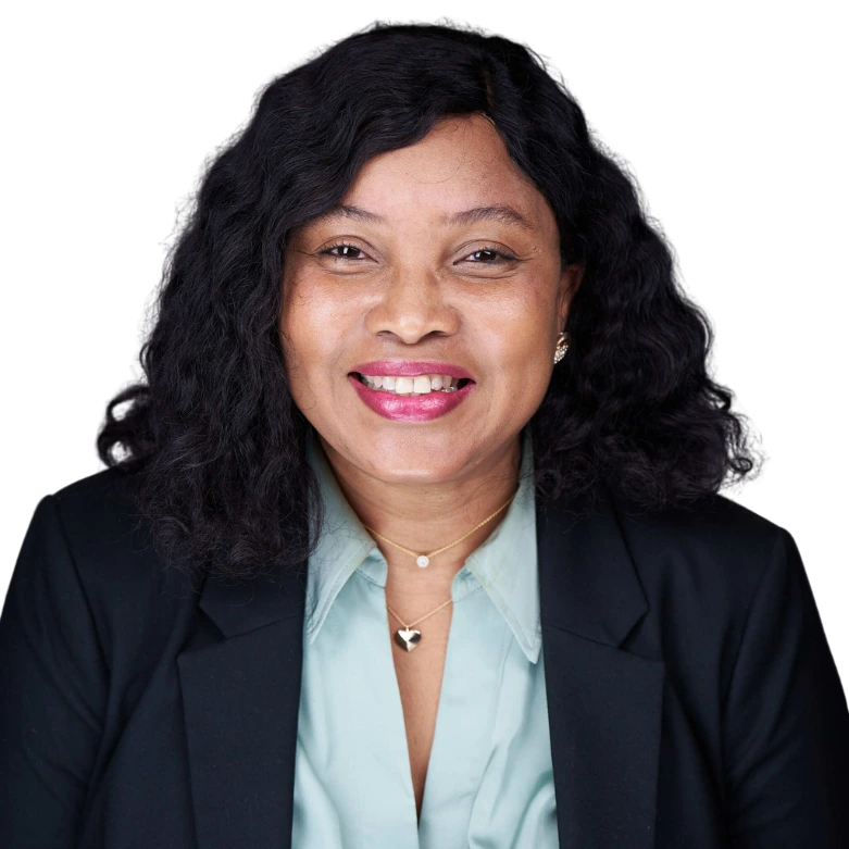 Smiling woman with long curly hair wearing a blazer and light blue shirt, white background.
