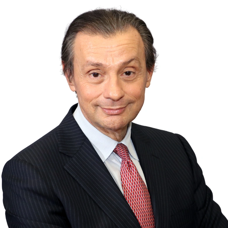 Portrait of a man in a suit and red tie, smiling against a white background.