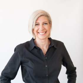 Smiling person with short blonde hair in a black shirt against a white background.