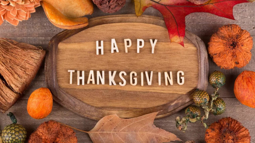 Happy Thanksgiving sign with autumn leaves and rustic decorations on wood background.