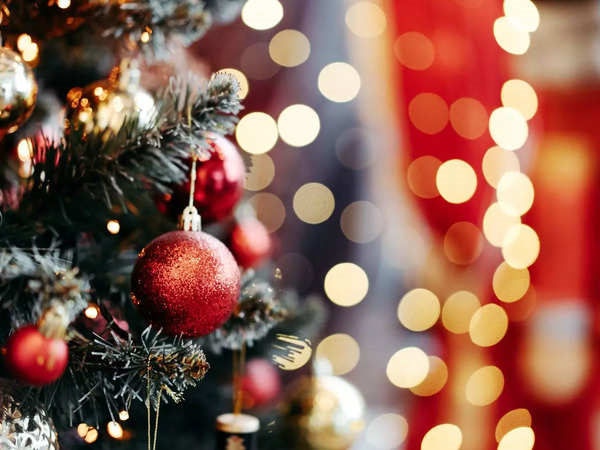 A close-up of a decorated Christmas tree with red ornaments and blurred holiday lights in the background.