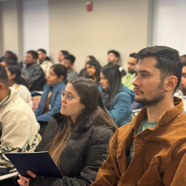 An audience of students attentively listening during an orientation.