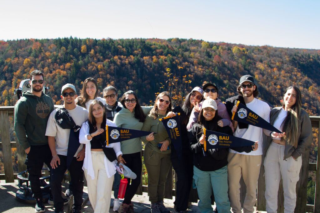 IMG_5558 (1) Group of students from Bay Atlantic University posing outdoors with autumn forest backdrop.