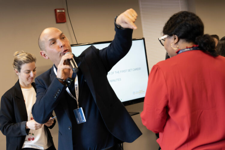 Man speaking with microphone during business presentation as attendees engage.