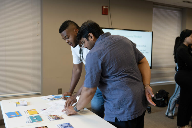 Two people collaborating over documents on a table during a workshop or meeting.