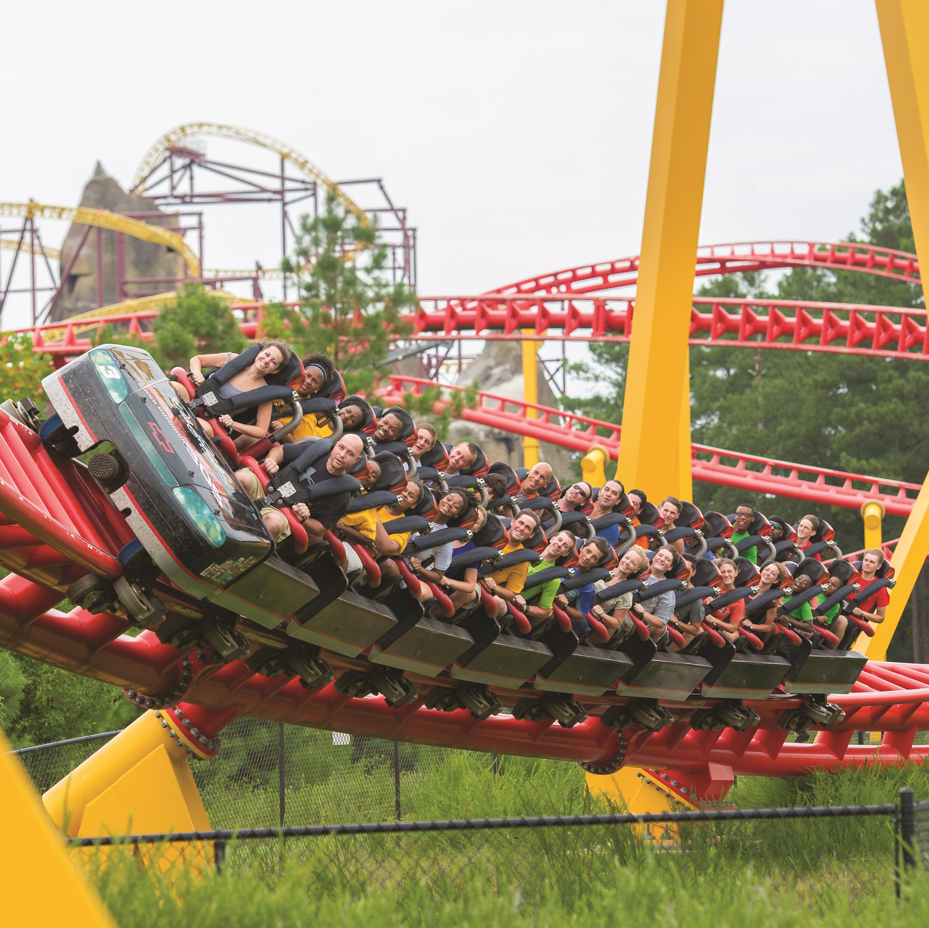 Thrilling roller coaster ride with passengers on curved red track at an amusement park.