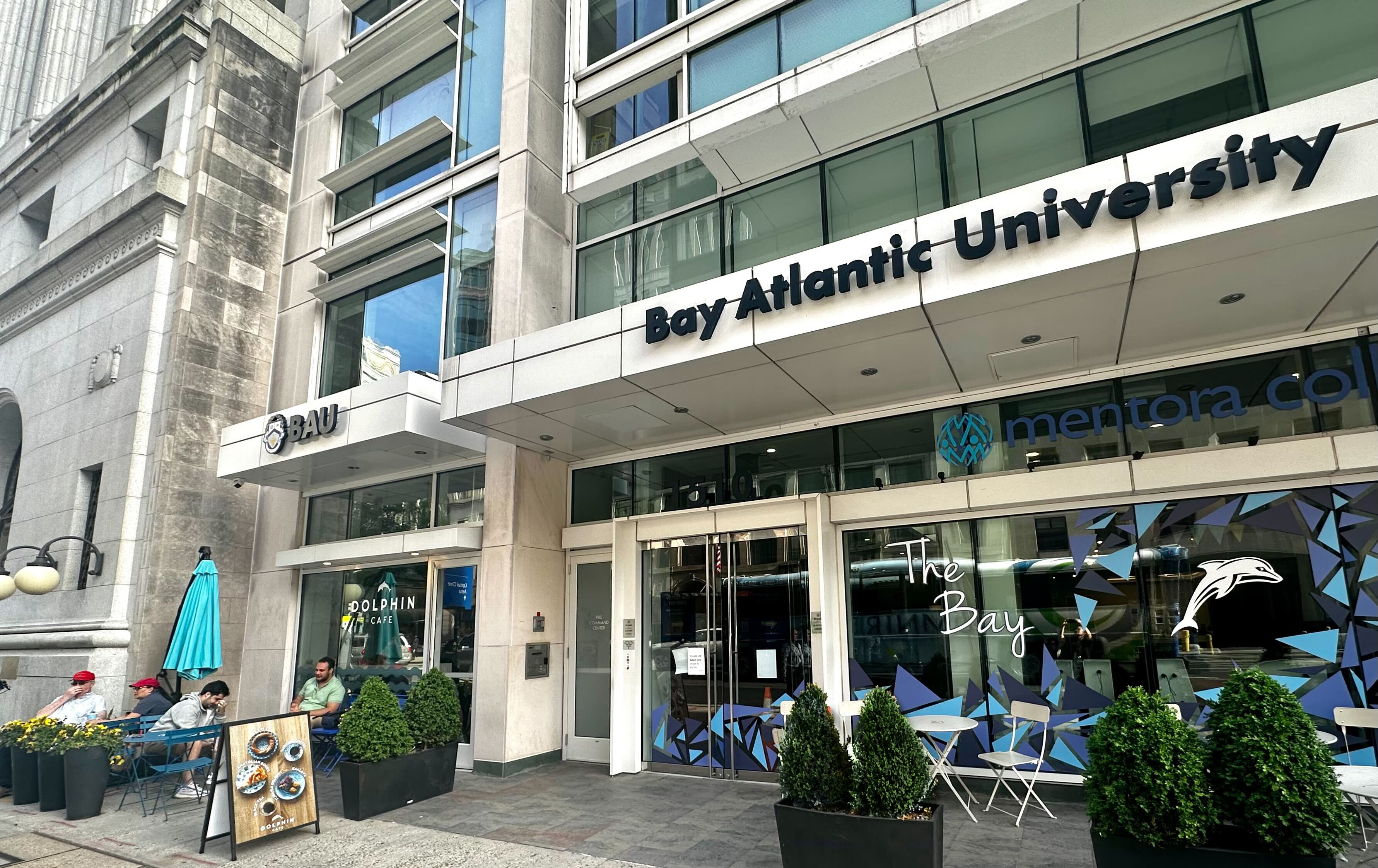 Entrance of Bay Atlantic University with outdoor seating and plants on a city street.
