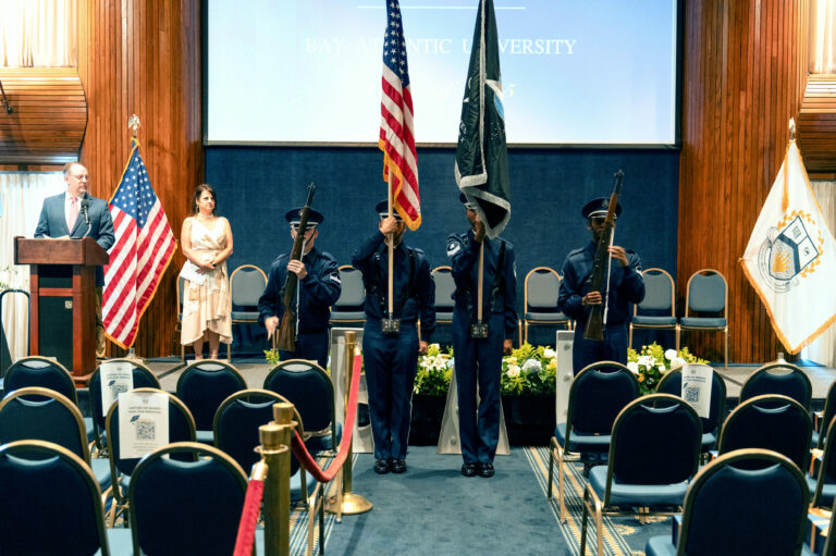 Color guard ceremony at Bay Atlantic University, featuring flag presentation with uniformed officers on stage.