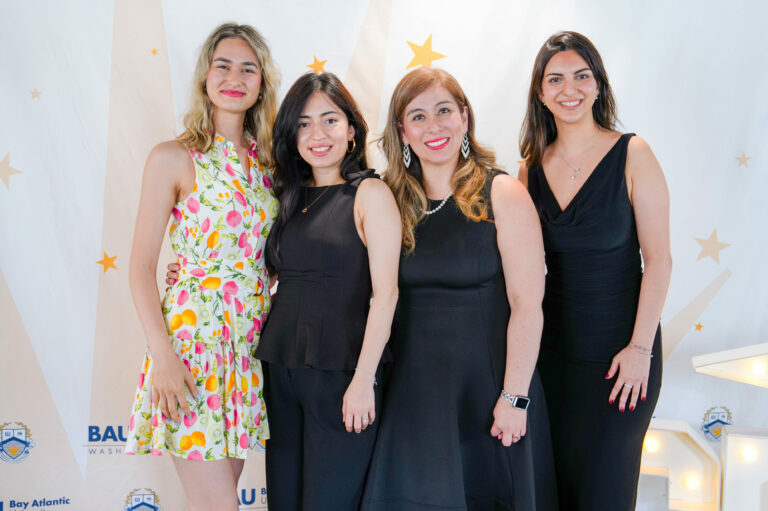 Four women posing together at an event, smiling, with a starry backdrop.