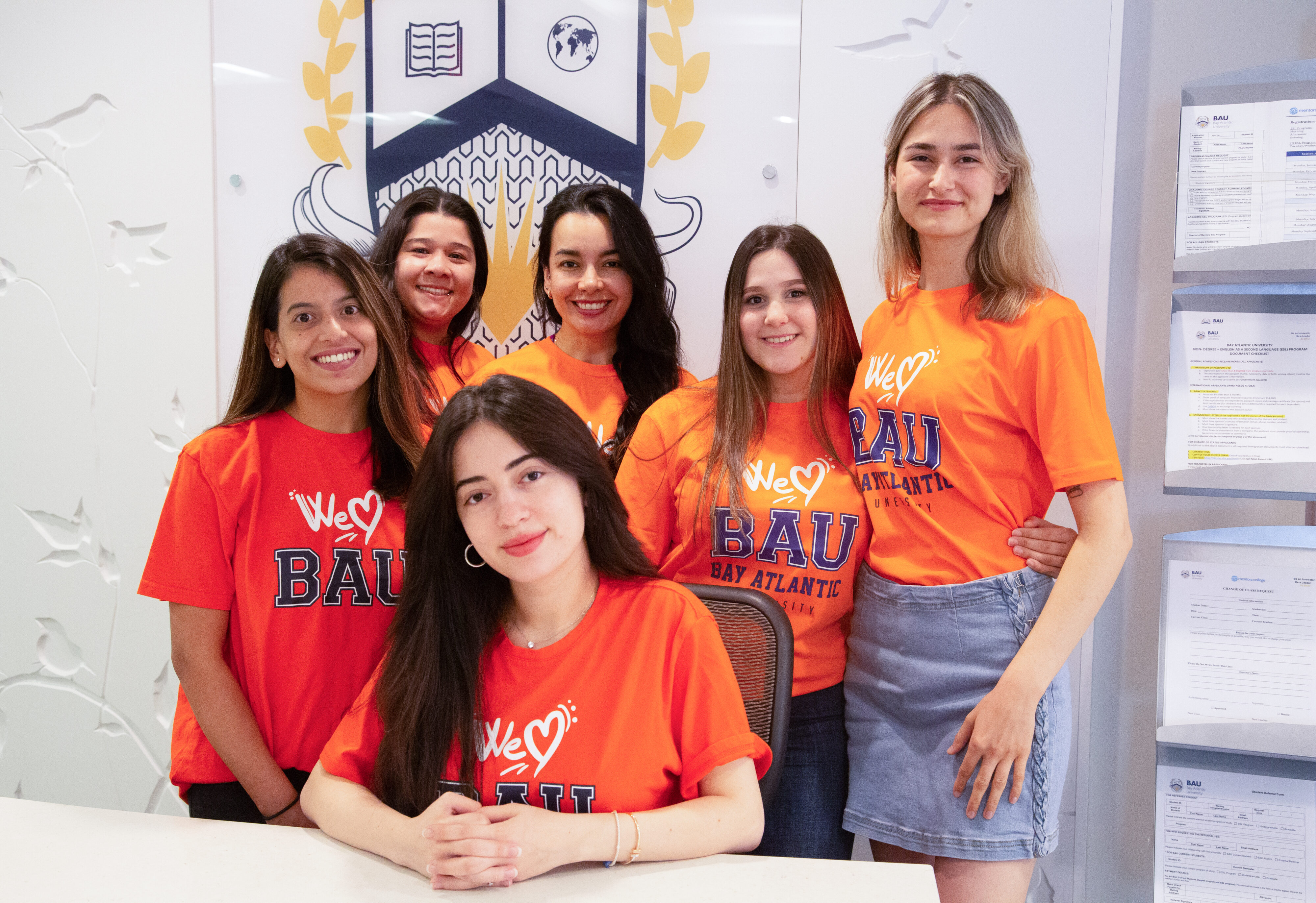 Group of women wearing orange We Love BAU shirts, smiling at a Bay Atlantic University event.