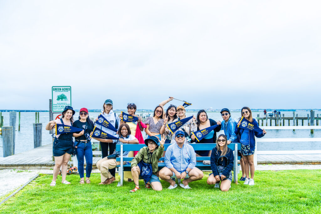 36-DSC00480 Group of people by a waterfront holding pennants, enjoying a cloudy day at the park.