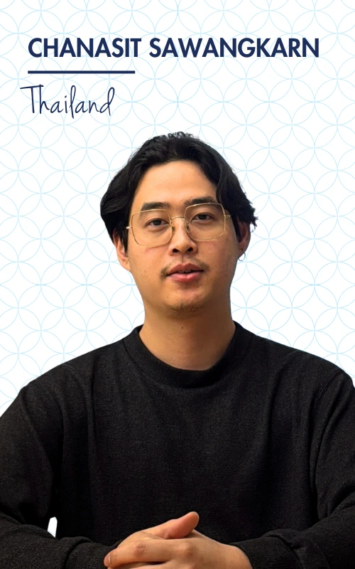 ```markdown
Portrait of a person from Thailand wearing glasses and a black sweater, with a patterned background.
```