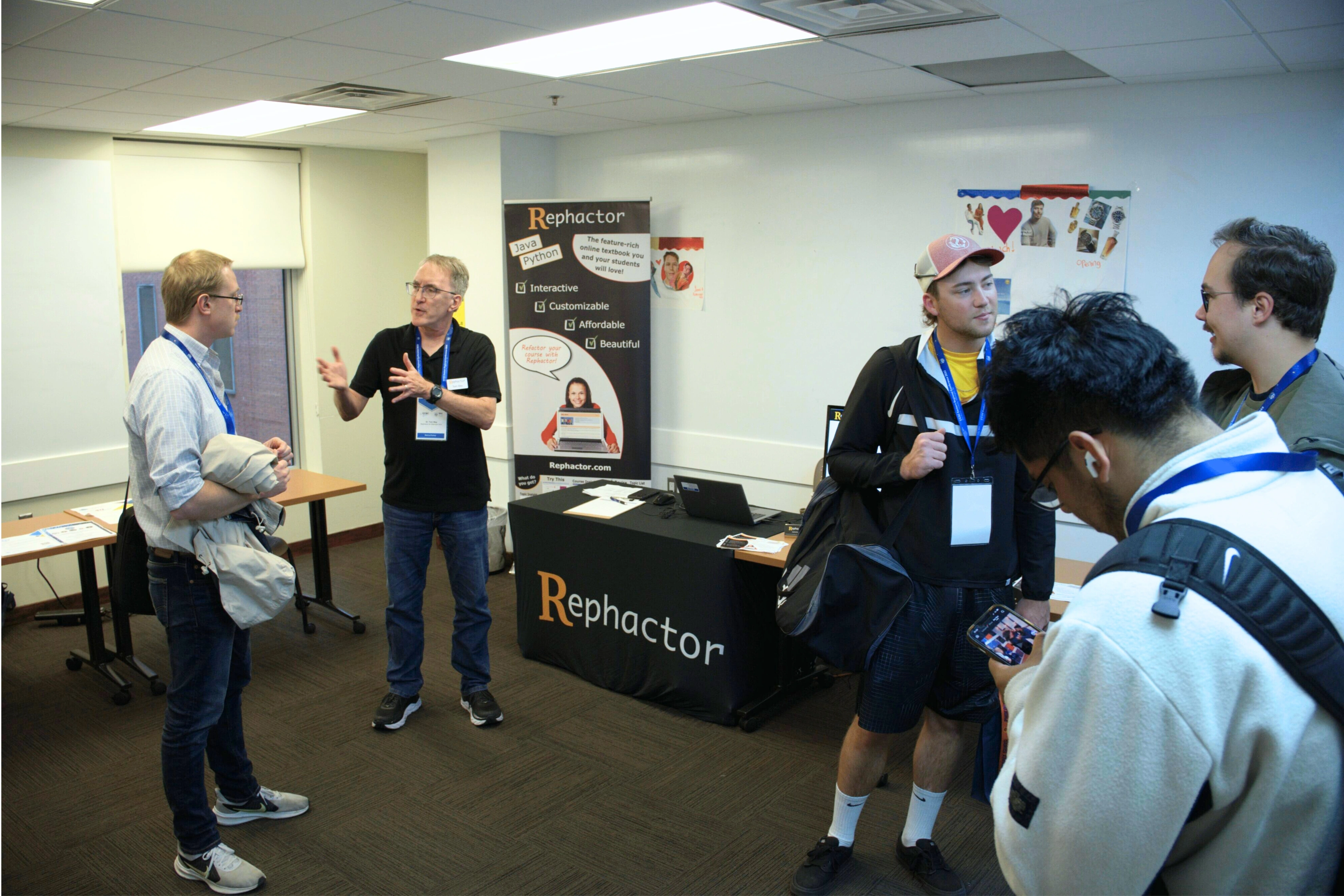 People networking at a tech conference, engaging with a Rephactor software booth.