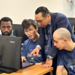 Professor guiding diverse students in a computer lab at Bay Atlantic University.