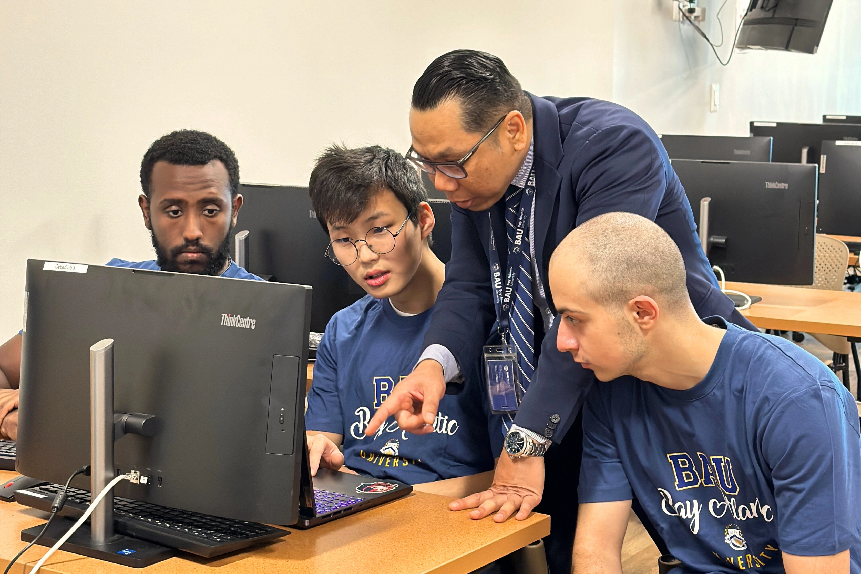 Professor guiding diverse students in a computer lab at Bay Atlantic University.