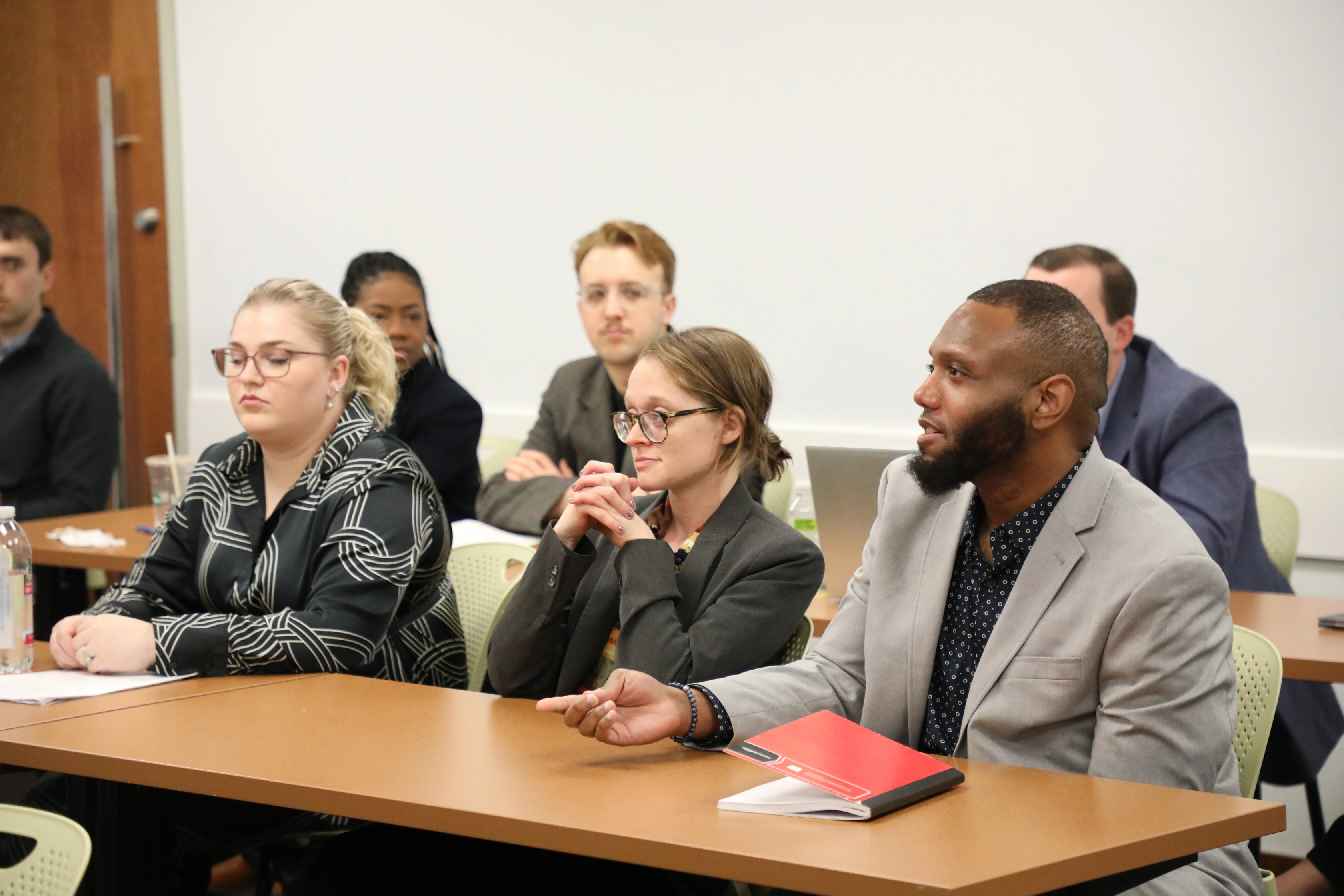 People attentively listening and participating in a business meeting at a conference room table.