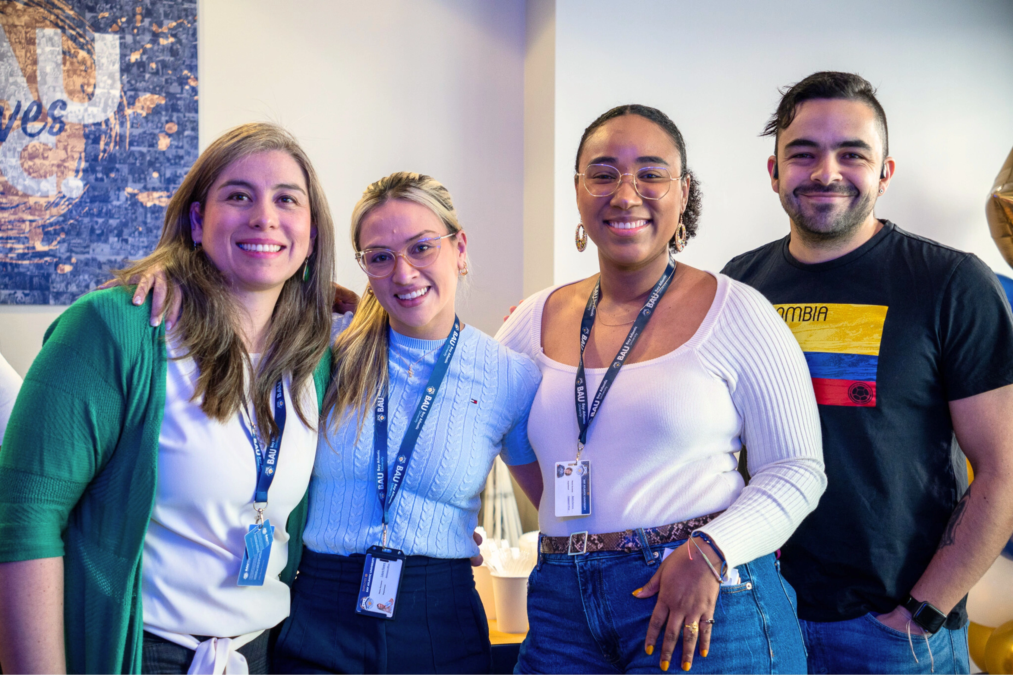 Group of four people smiling at an event, wearing ID badges and casual outfits.