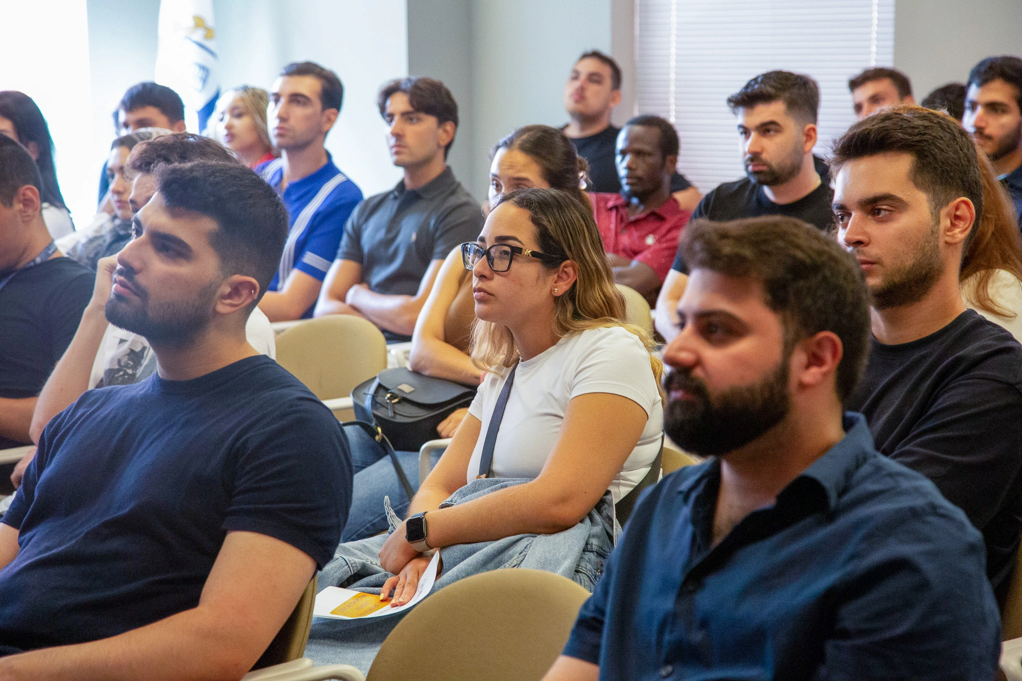 Audience attentively listening at a conference, diverse group of young professionals engaged and focused.