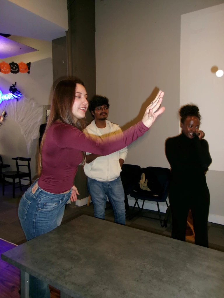 SGA Halloween Party 2025 A woman playing beer pong at a Halloween party, with friends watching.