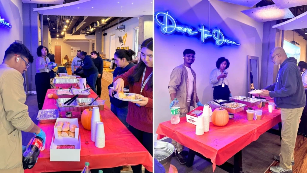 Office potluck with employees serving food from a buffet table under blue Dare to Dream neon sign.