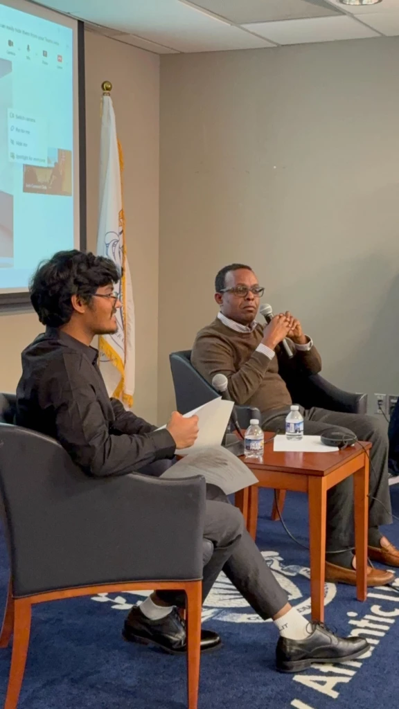 Tech Connect Event with Student Government Association 2025 Two men engaging in a panel discussion in a conference room, with one holding a microphone.