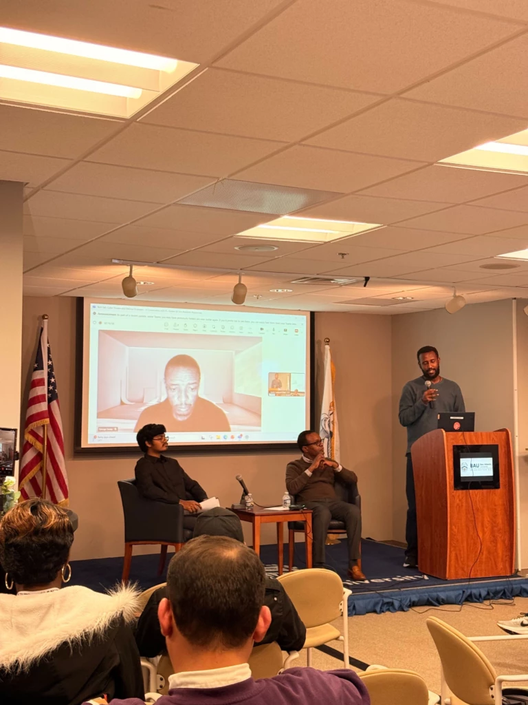 Tech Connect Event with Student Government Association 2025 Panel discussion with speaker at podium, audience seated, and video call screen in conference room.