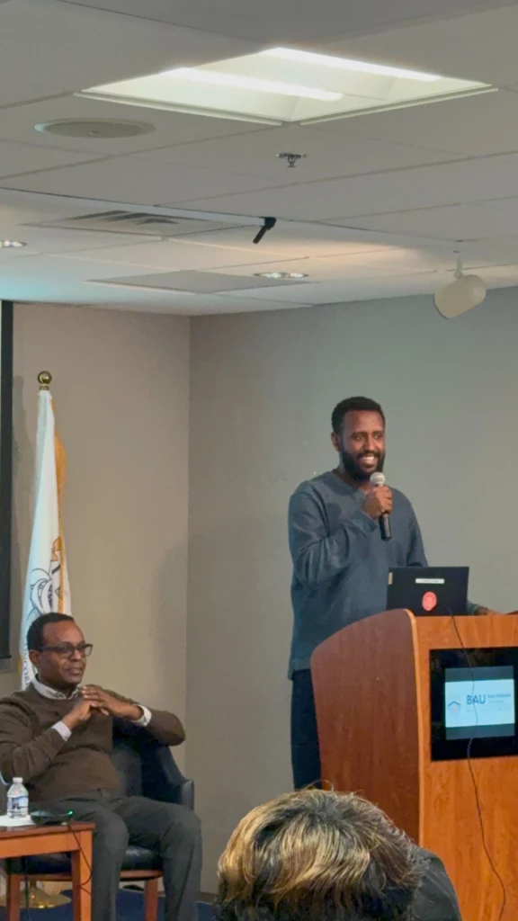 Tech Connect Event with Student Government Association 2025 Man speaking at a podium with an audience, conference flag in background. African Union event setting.