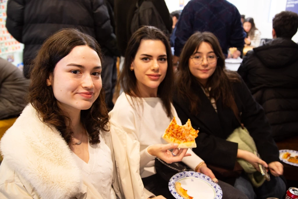 Three friends enjoying a slice of pizza together at a casual gathering.