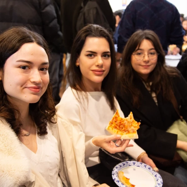 Three friends enjoying a slice of pizza together at a casual gathering.