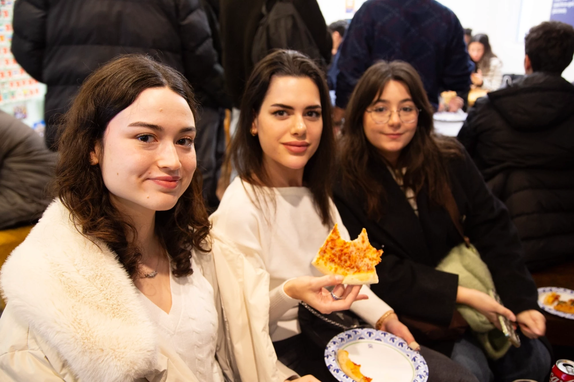 Three friends enjoying a slice of pizza together at a casual gathering.