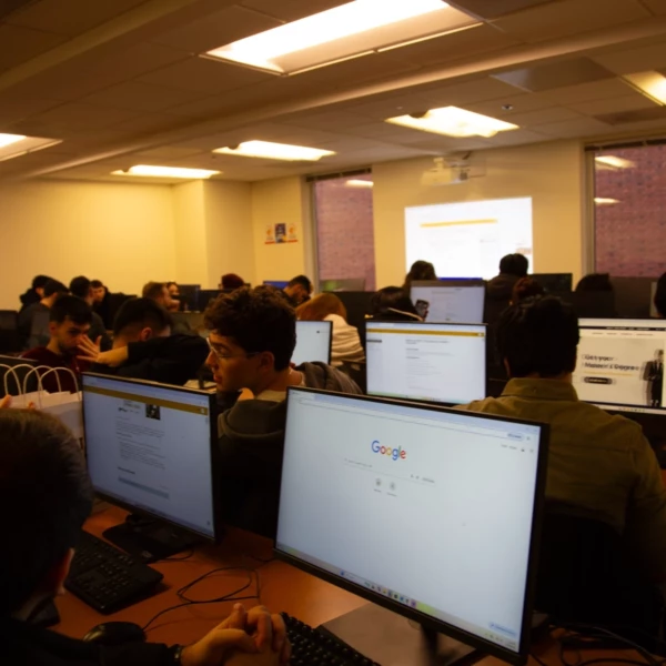 Students engaged in a computer lab class with multiple screens displaying educational content.