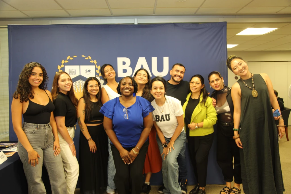 Group of diverse people smiling in front of a BAU banner at an event.
