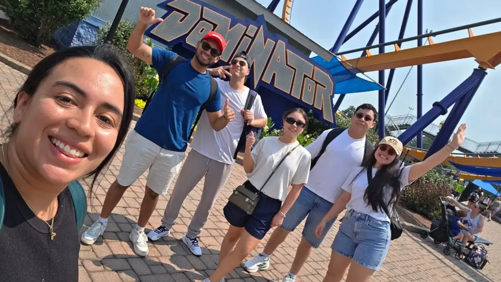 Group of friends enjoying a day at the amusement park, posing in front of the Dominator roller coaster entrance.