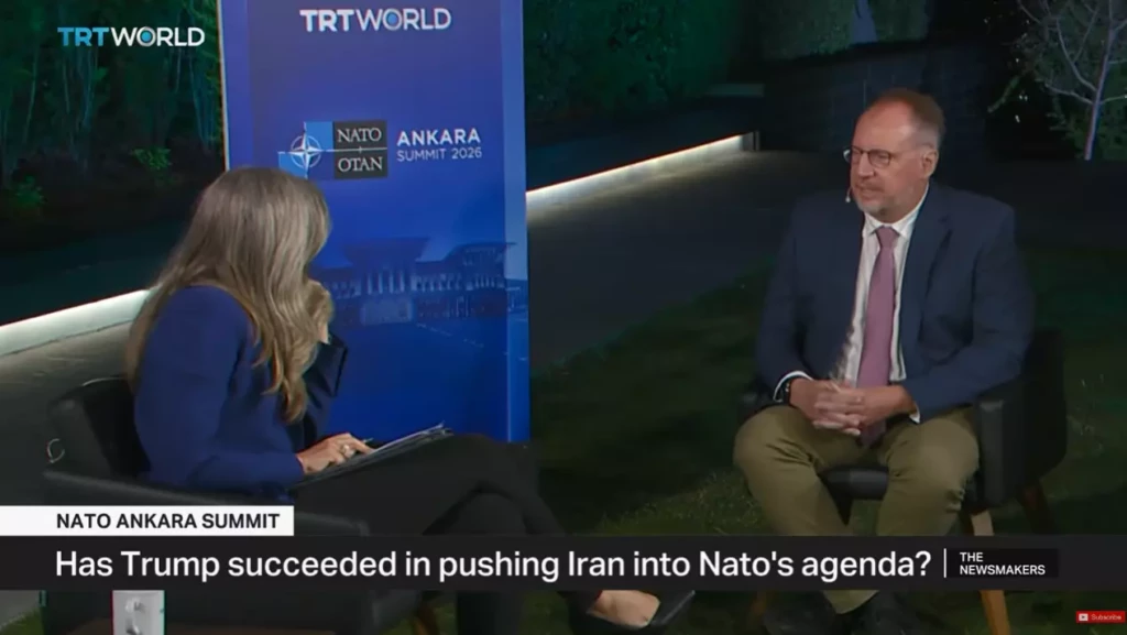 Dr. Sean Michael Cox being interviewed by a female host on TRT World's The Newsmakers broadcast during the 2026 NATO Ankara Summit. The on-screen graphic reads "Has Trump succeeded in pushing Iran into Nato's agenda?"