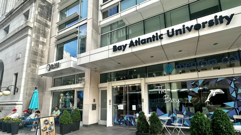 Exterior view of Bay Atlantic University entrance with nearby Dolphin Cafe and outdoor seating area.