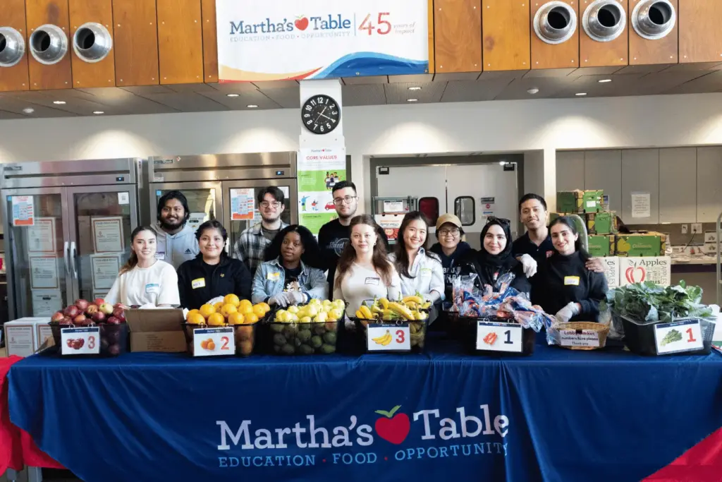 BAU Program Images (70) Volunteers distribute fresh produce at Martha's Table community event, under a banner celebrating 45 years of impact.