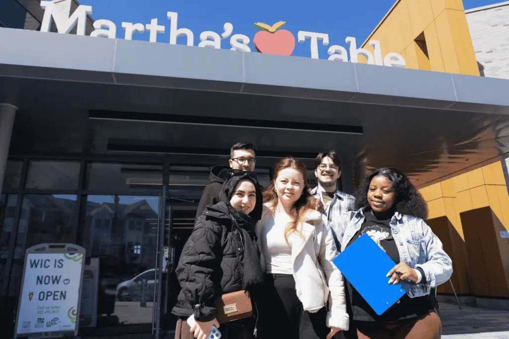 BAU Program Images (71) Group of diverse people smiling outside Martha's Table community center, promoting unity and engagement.